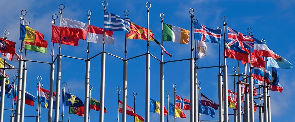Fahnen europäischer Länder an Masten vor blauem Himmel